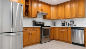 A modern kitchen with wooden cabinets, stainless steel appliances, and a marble backsplash. - Marbella Lane - 4BR Alluring Home (Union City)