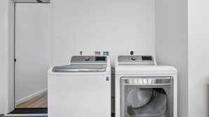 A laundry room with two white front-loading washing machines and a dryer. - Marbella Lane - Spacious 2BR Home 17-min to Levi's (San Jose)