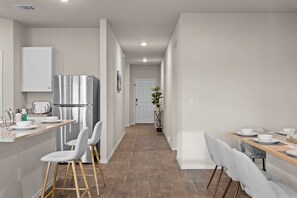 A modern kitchen with stainless steel appliances, a bar stool seating area, and a dining table set for four. - Marbella Lane - Amazing 4BR Lakeview Home (Austin)