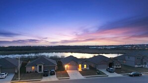 A residential area with houses, a body of water, and a sunset sky. - Marbella Lane - Amazing 4BR Lakeview Home (Austin)