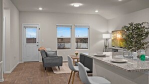 A modern kitchen with a granite countertop, a dining area with a gray sofa and chairs, and a view through the windows. - Marbella Lane - Amazing 4BR Lakeview Home (Austin)