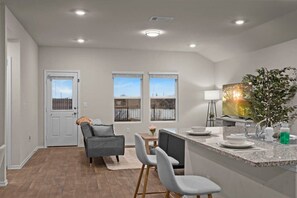 A modern kitchen with a granite countertop, a dining area with a table and chairs, and a view through the windows. - Marbella Lane - Amazing 4BR Lakeview Home (Austin)