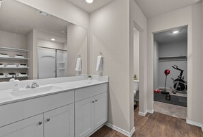 A modern bathroom with a large mirror, white cabinetry, and a shower area. - Marbella Lane - Amazing 4BR Lakeview Home (Austin)