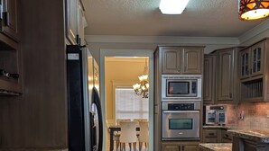 A kitchen with wooden cabinets, a refrigerator, an oven, and a microwave. - 2651 sqft - Fenced Backyard / Firepit / 5m to LR (Bryant)