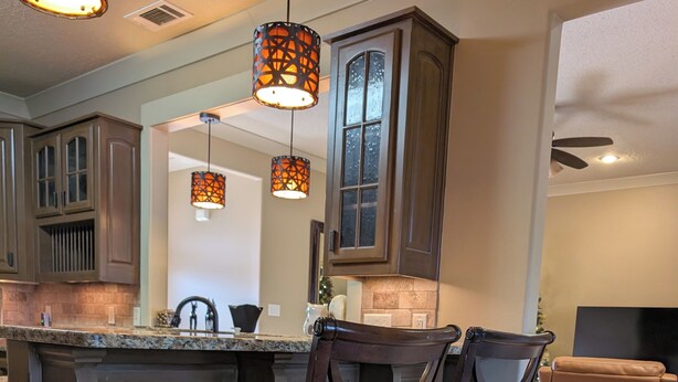 A kitchen with dark wooden cabinets, a granite countertop, and two bar stools. - 2651 sqft - Fenced Backyard / Firepit / 5m to LR (Bryant)