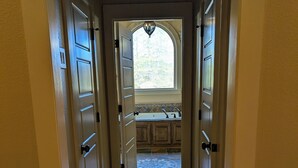A hallway leading to a kitchen with a window and a tiled backsplash. - 2651 sqft - Fenced Backyard / Firepit / 5m to LR (Bryant)
