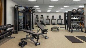 Ein Fitnessstudio mit verschiedenen Trainingsgeräten, Laufbändern und Kurzhanteln.