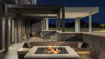 An outdoor seating area with a fire feature and a covered patio.