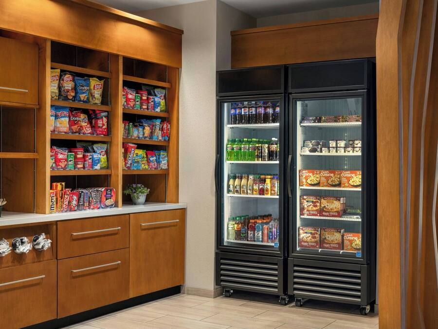 A kitchen with wooden cabinets, a refrigerator, and various food items.