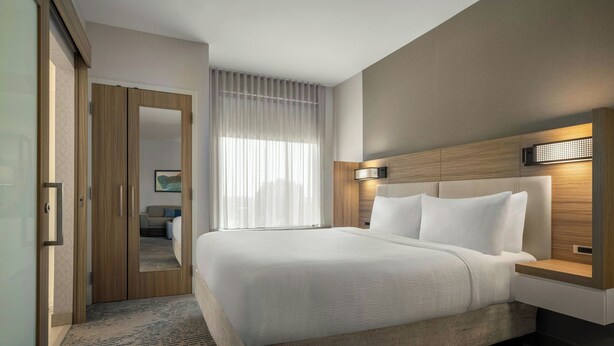 Ein Hotelzimmer mit einem großen Bett, einem Holzkopfstück, einem Nachttisch und einem Spiegel.