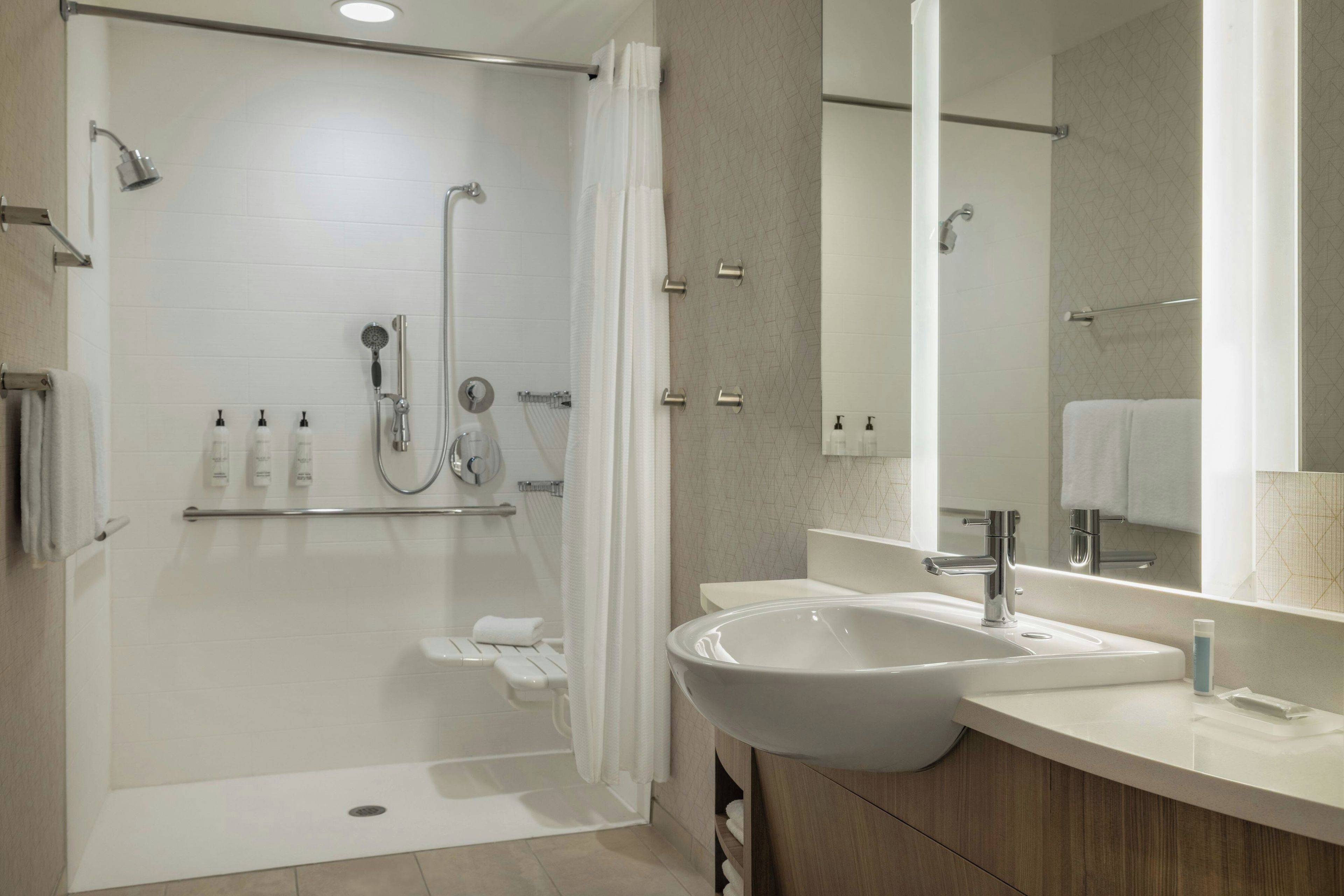 A modern bathroom with a walk-in shower, a sink, and a mirror.