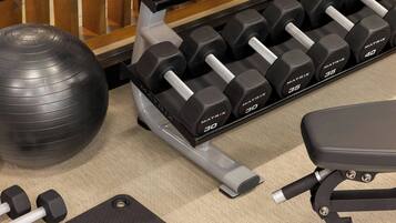 A gym with a variety of equipment including dumbbells, a medicine ball, and a bench.
