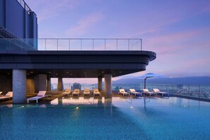A rooftop infinity pool with lounge chairs and a glass balustrade overlooking a cityscape. - Marriott Executive Apartments Danang, Han River (Da Nang)