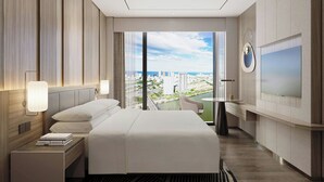 Habitación de hotel moderna con una cama grande, un televisor y vistas a la ciudad.
