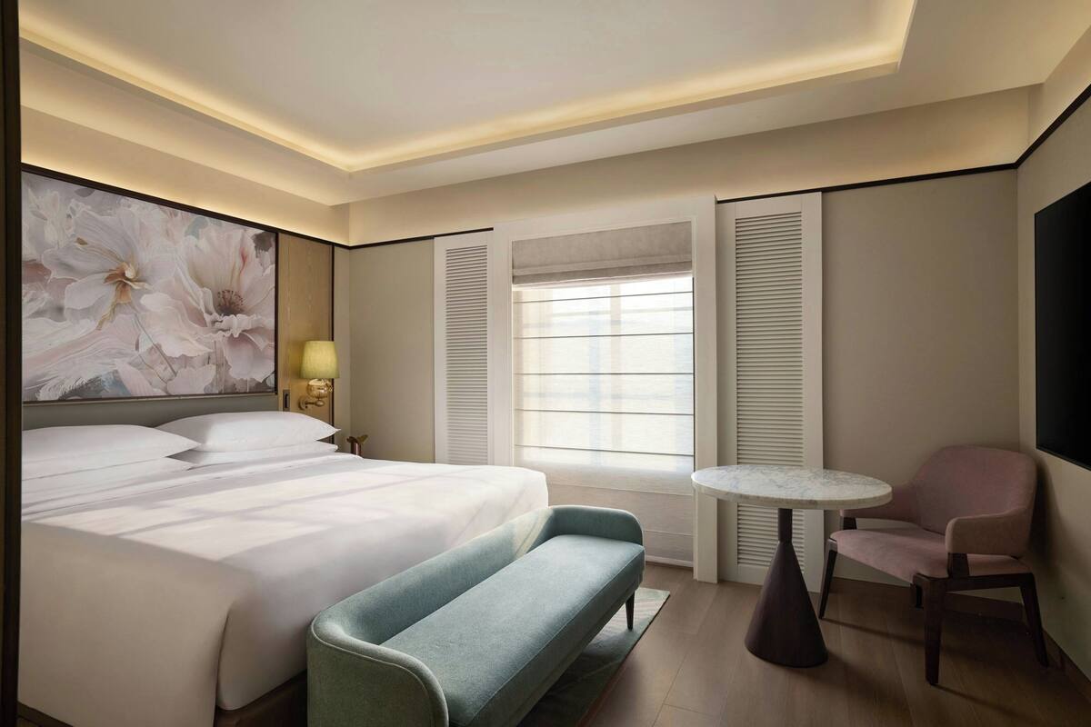 Ein Hotelzimmer mit einem großen Bett, einer Bank, einem kleinen Tisch und einem Stuhl.