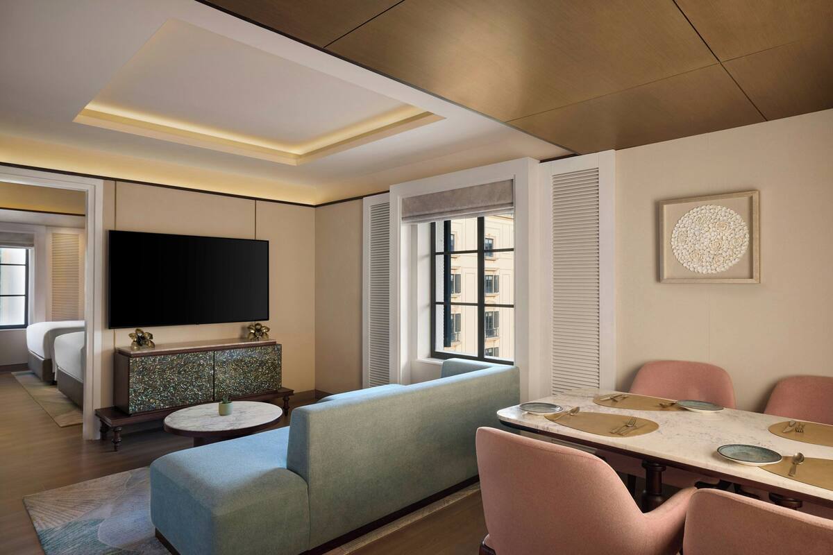 Ein modernes Hotelzimmer mit Sofa, Esstisch und Fernseher.