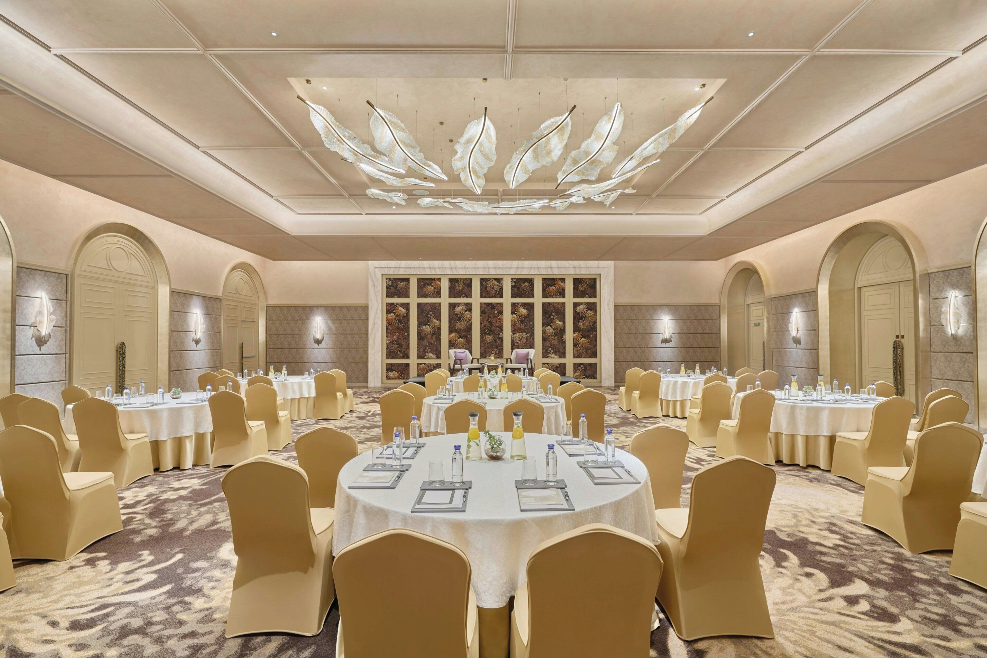 A large conference room with round tables, beige chairs, and a decorative ceiling.