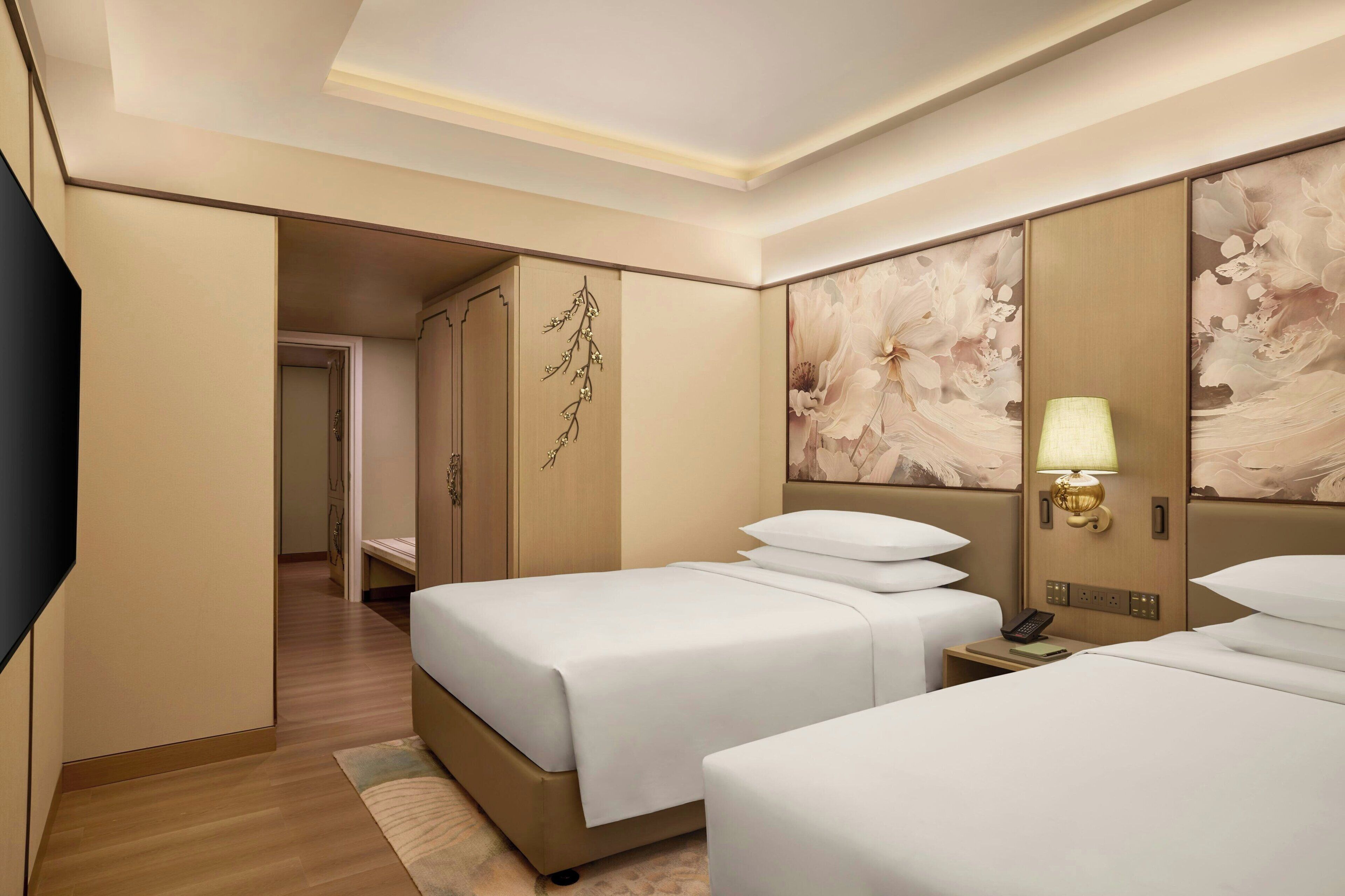 Ein Hotelzimmer mit zwei Betten, einem Nachttisch mit Lampe und einem an der Wand montierten Telefon.