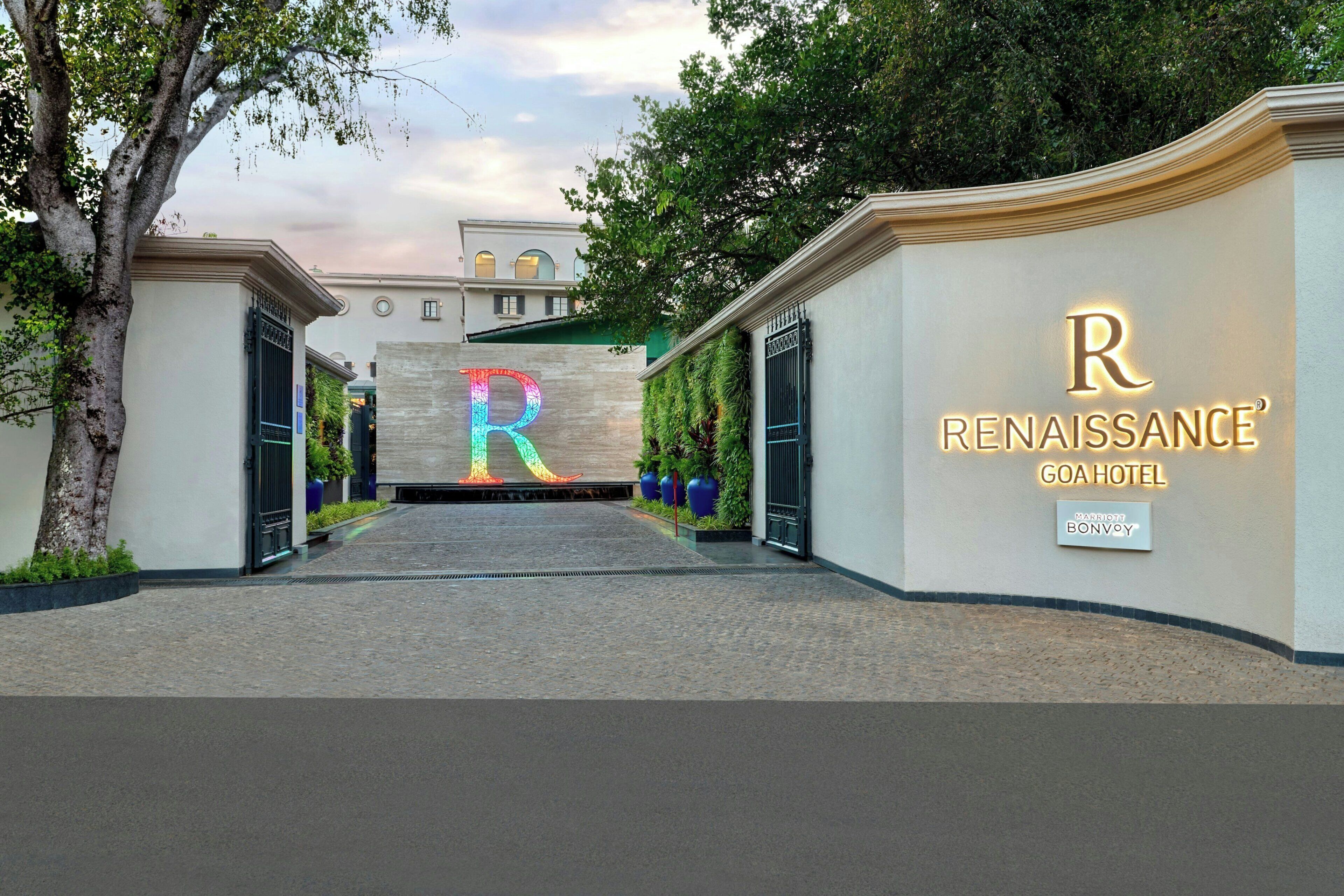 Entrada de un hotel con una gran 'R' iluminada y el nombre 'Renaissance Goa Hotel'.