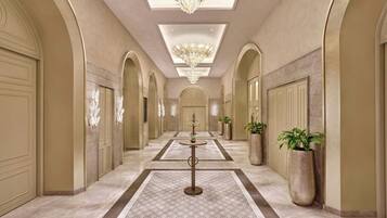 A hallway with arched ceilings, chandeliers, and potted plants.