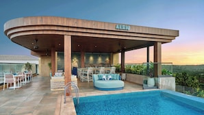 A modern building with a pool, outdoor seating, and a view of the landscape. - Renaissance Goa Hotel (Arpora)