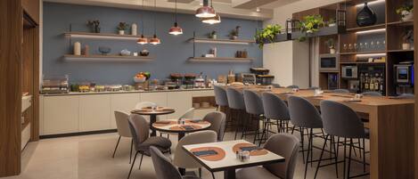 A modern restaurant with a central island, multiple seating areas, and a variety of plants and kitchen appliances.