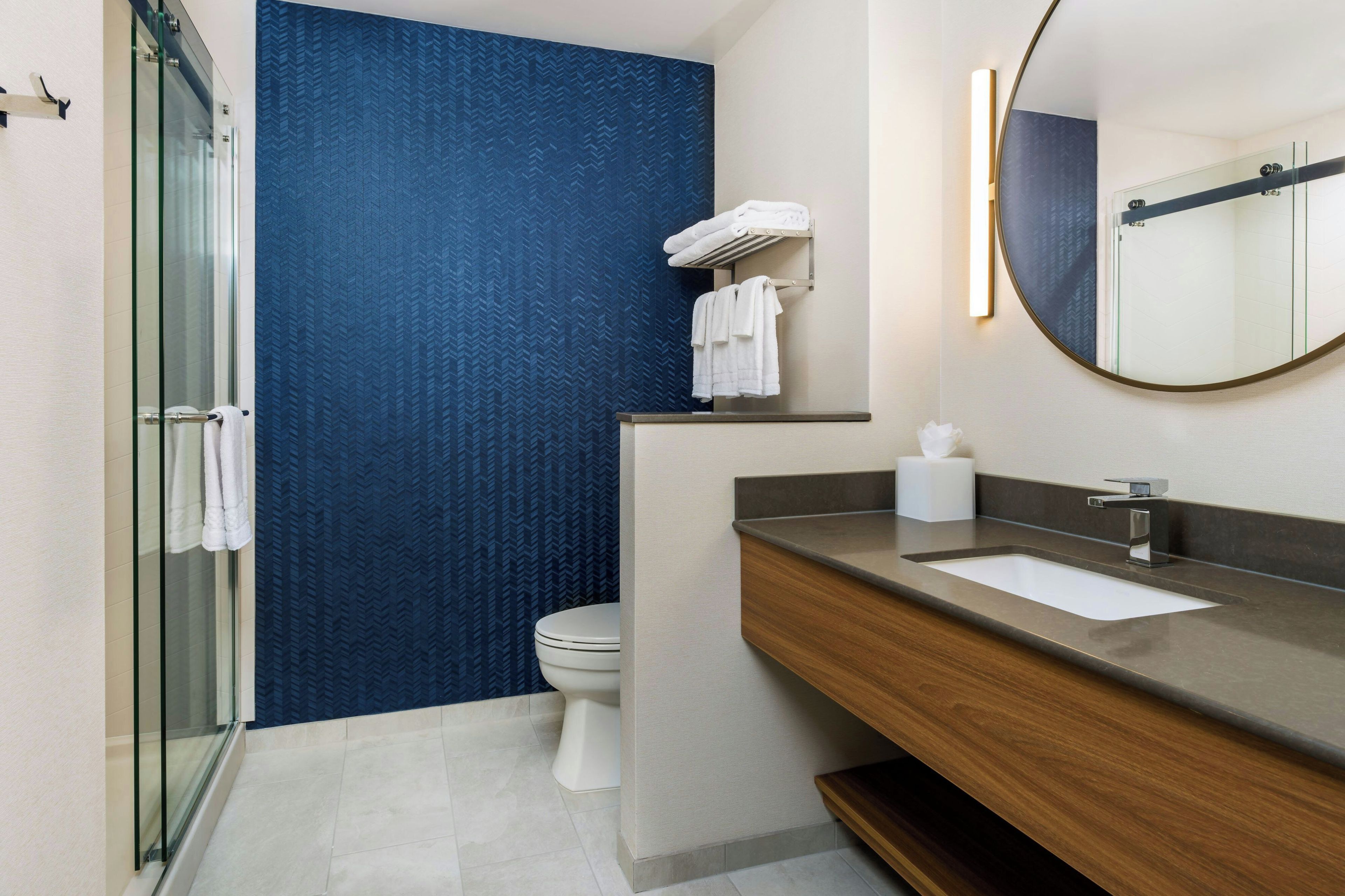 Un bany modern amb plat de dutxa de vidre, un vàter i un lavabo amb rentapla i mirall.