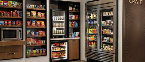 Un área de autoservicio para aperitivos y bebidas, con refrigeradores y un microondas.