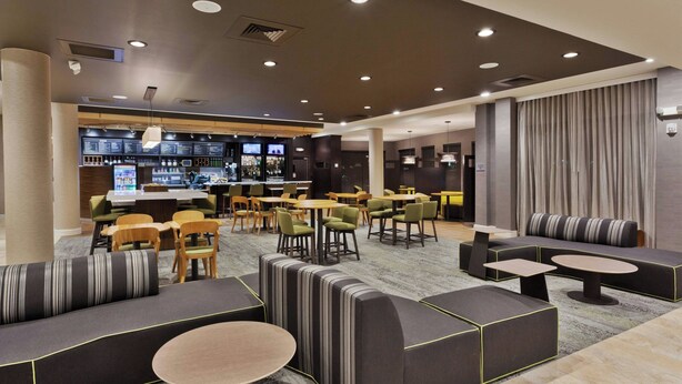 Un espace de détente moderne, doté de différents types de sièges, d’un bar et d’un écran de télévision.