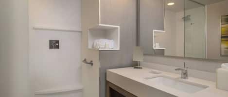 A modern bathroom with a large mirror, two sinks, and a shower.
