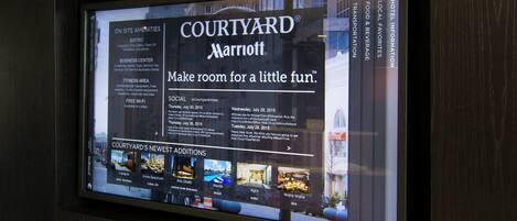A digital display of Courtyard Marriott amenities including a bistro, business center, fitness area, and Wi-Fi availability.