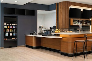 Zona de bar moderna con mostrador, taburetes, dispensador de bebidas y una variedad de opciones.