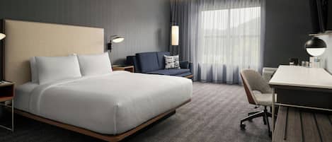 Une chambre d’hôtel avec un lit, un bureau, une chaise, une télévision et une fenêtre avec des rideaux.