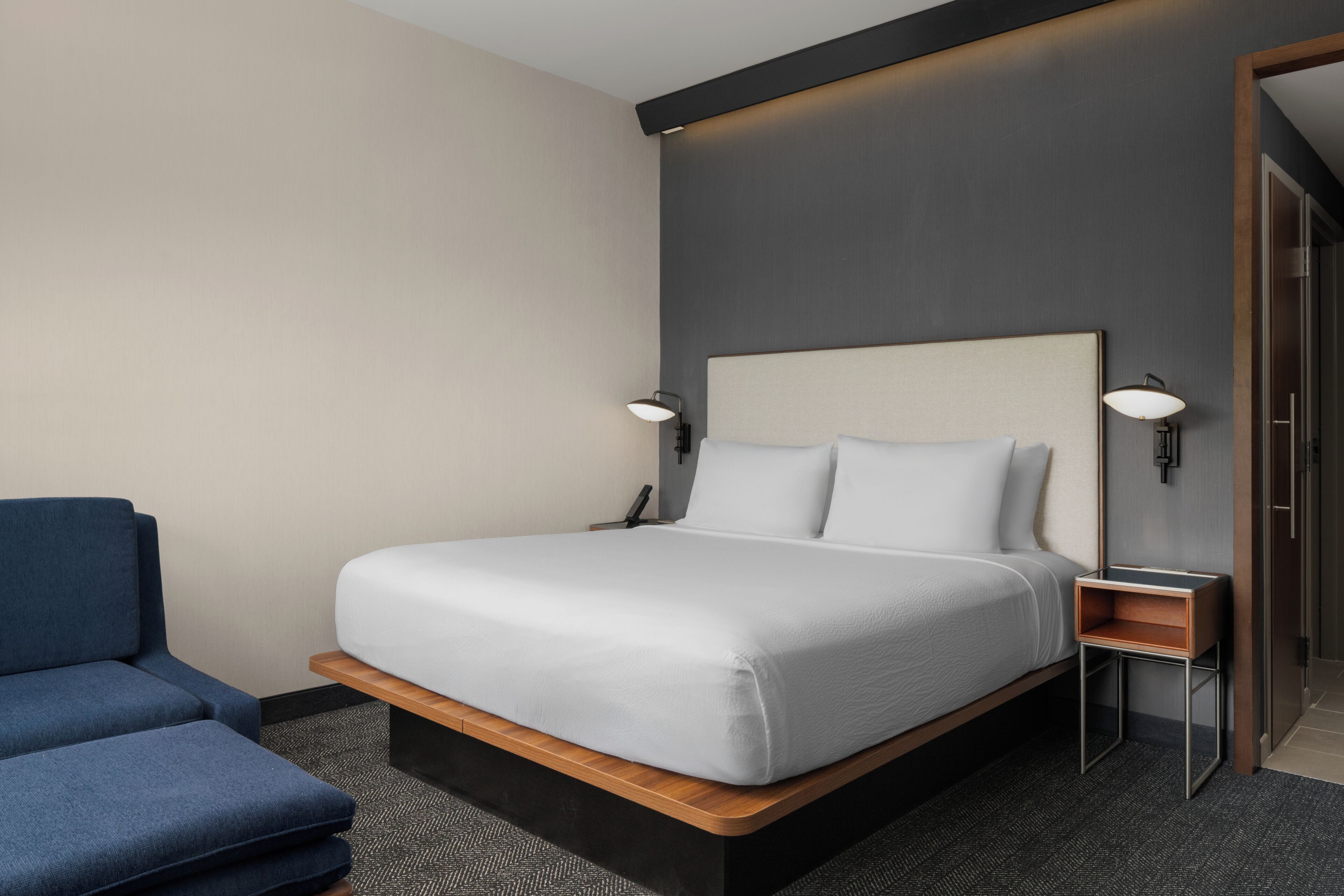 Een hotelkamer met een bed, een stoel en een nachtkastje.