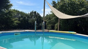 A swimming pool with a wooden deck and metal ladders.