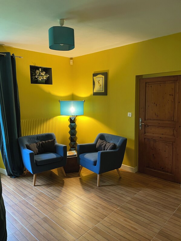 A room with two blue armchairs, a lamp, a wooden door, and a radiator. - Les Trois Moulins - Your destination for Zenitude and a host of activities (Tonnay-Charente)