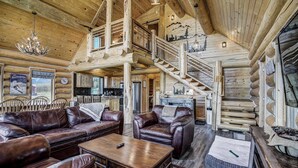 A log cabin interior with a wooden staircase, leather sofas, and a chandelier. - Thick Spike Lodge - Huge space for the whole group! (Fairplay)