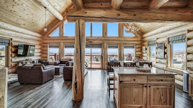 A spacious log cabin interior with a large living area, a kitchen with wooden cabinets, and large windows offering views of the outdoors. - Thick Spike Lodge - Huge space for the whole group! (Fairplay)