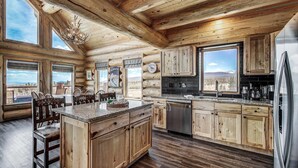 A log cabin kitchen with wooden cabinets, a large island, and a view of the mountains. - Thick Spike Lodge - Huge space for the whole group! (Fairplay)