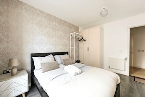 Une chambre à coucher comprenant un lit, des tables de chevet, un luminaire suspendu et une armoire.