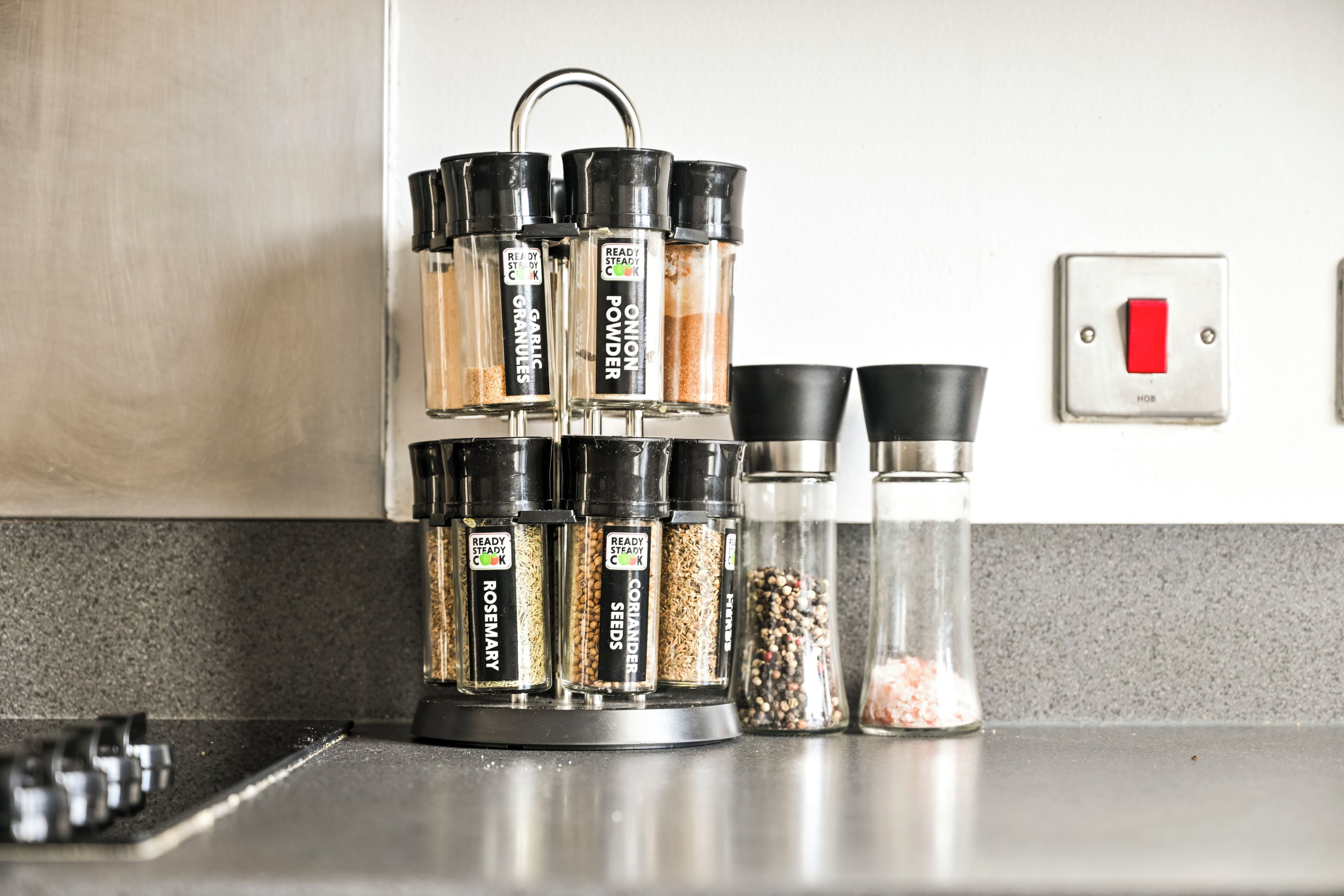 A kitchen with a spice rack holding containers labeled with various spices.