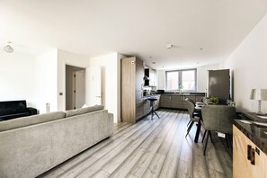 A modern kitchen with a dining area, a sofa, and a view of the outside. - Spacious 3-bed Apartment in Stratford | Free Parking & Terrace (Greater London)
