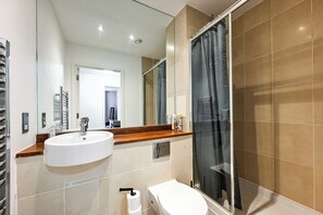 Un baño moderno con lavamanos, inodoro y zona de ducha.