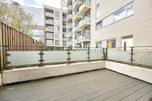 Une cour intérieure urbaine moderne, agrémentée d’une clôture en bois, d’un mur de soutènement en béton et d’une rambarde en métal.