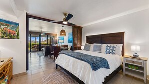 Een hotelkamer met een bed, een bureau, een stoel, uitzicht op zee en een balkon.