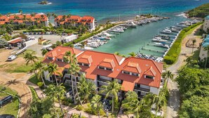 Een jachthaven met meerdere boten afgemeerd, omringd door resortgebouwen met rode daken en palmbomen.