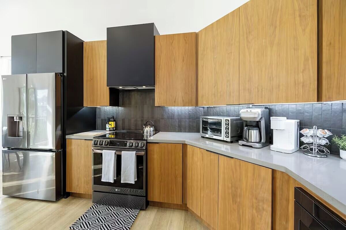 A modern kitchen with wooden cabinets, stainless steel appliances, a built-in oven, and a coffee maker.