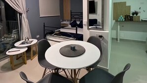 Uma sala moderna com espaço de jantar, uma cama e uma televisão.
