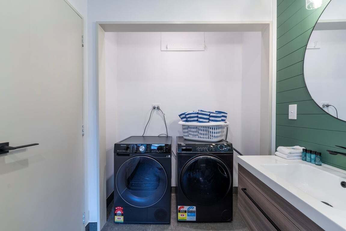 A compact laundry area with two washing machines and a basket of clothes.