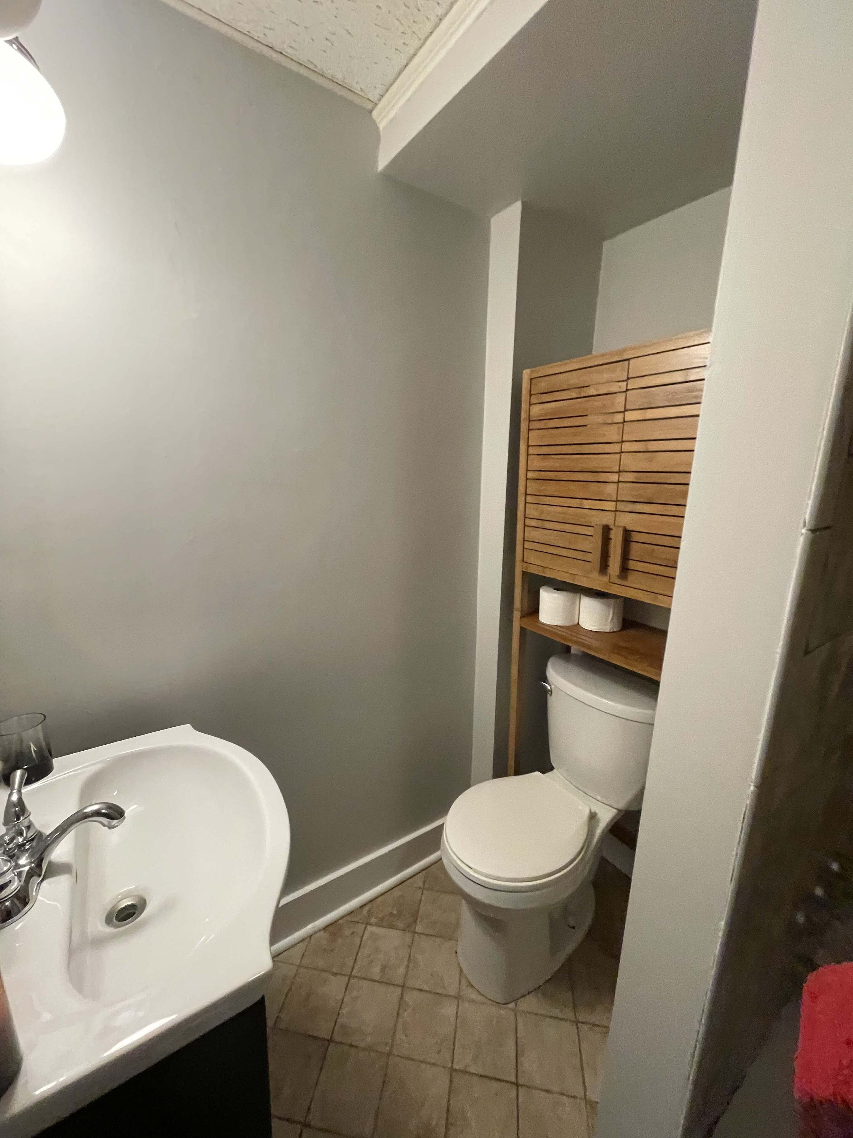 Une salle de bain avec un lavabo blanc, des toilettes et un meuble en bois.